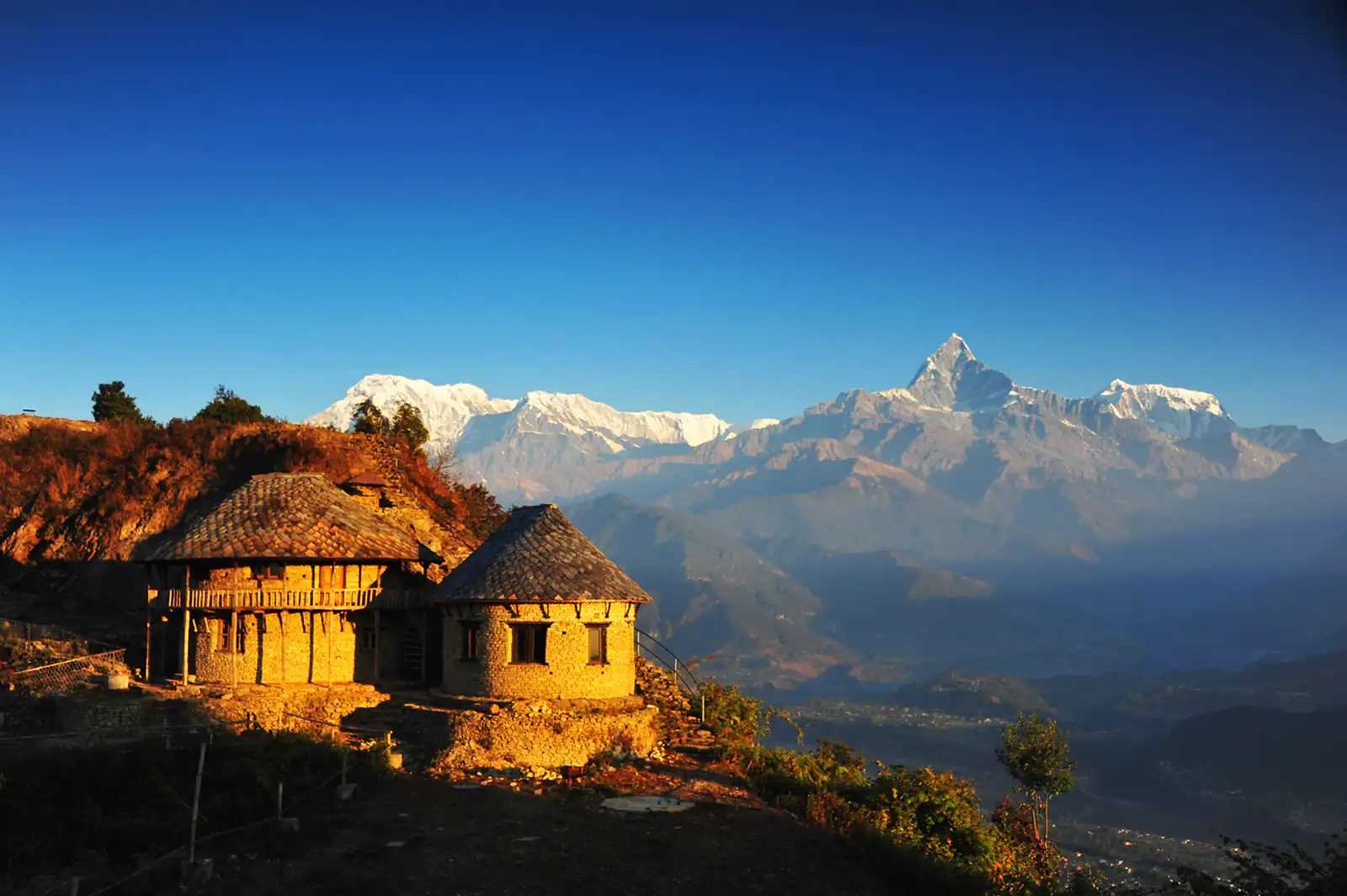 Traditional stone village above Pokhara at sunrise, with Machhapuchhre and the Annapurna range behind